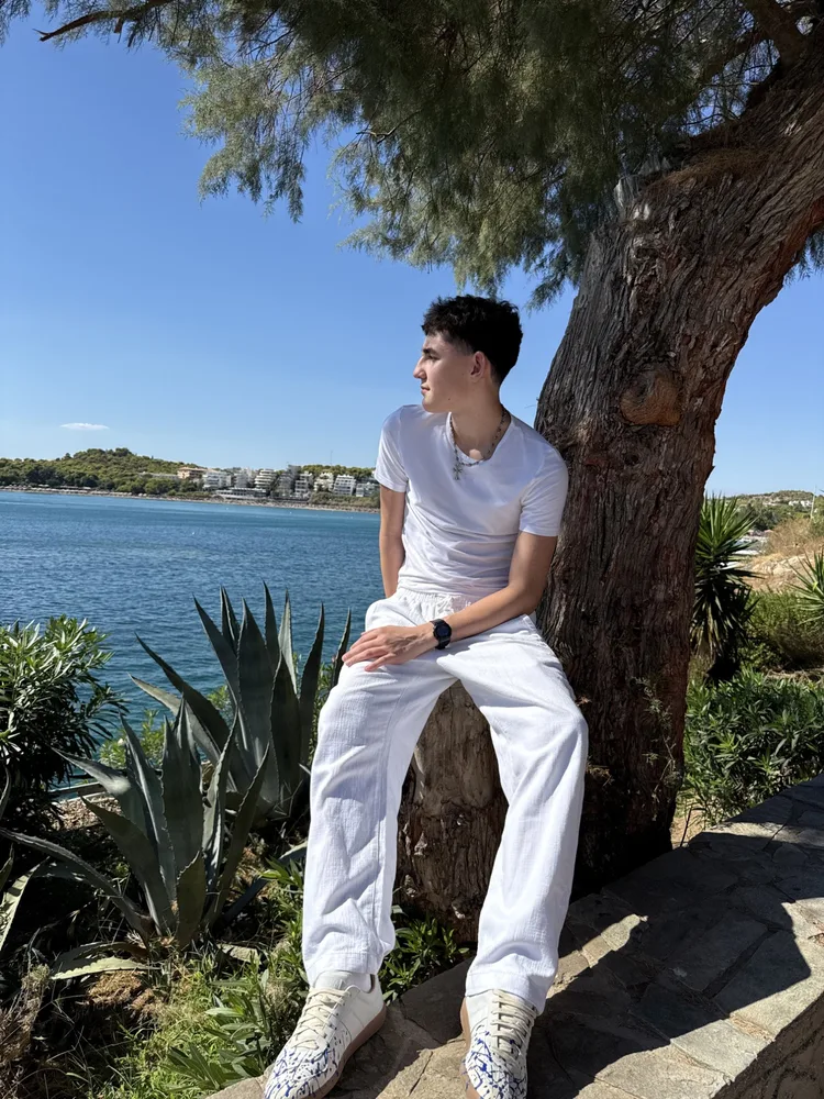 Steven sitting by the sea under a tree.